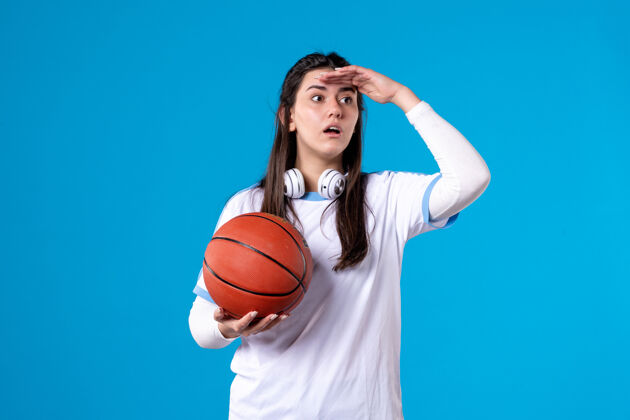 举行正面图：蓝色墙上挂着篮球的年轻女子蓝比赛青年