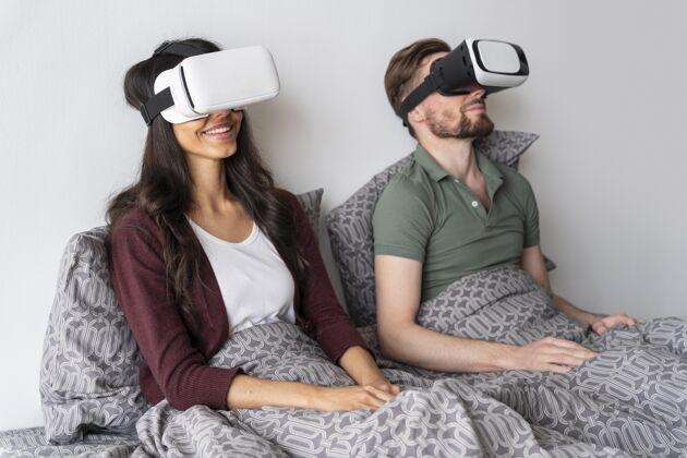 家庭侧视图笑脸的女人和男人使用虚拟现实耳机在床上床女人房子