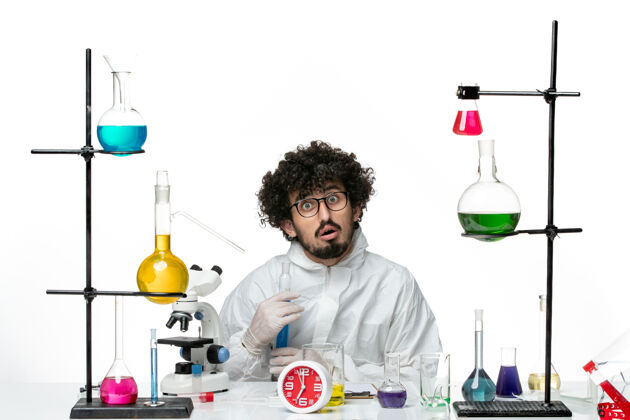 溶液正面图：年轻的男科学家 穿着特殊的衣服 在白色的桌子上拿着装有溶液的烧瓶套装容器烧杯