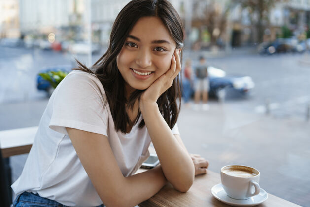 女孩可爱的亚洲女孩坐在咖啡桌上 喝着卡布西诺 微笑着休闲脸年轻人