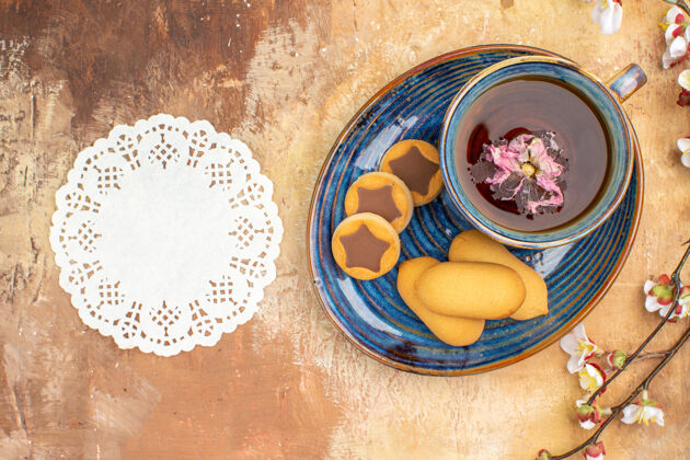 健康上图各种饼干一杯茶花和餐巾放在五颜六色的桌子上传统混合茶