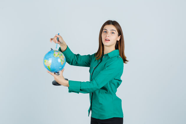 时尚年轻的女士拿着地球仪 穿着衬衫指着地球仪 看上去很困惑前视图女性微笑地球仪