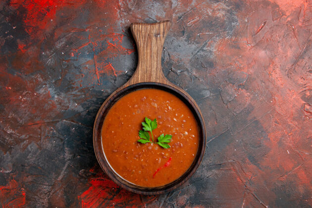 番茄经典的番茄汤放在棕色的砧板上 放在五颜六色的桌子上番茄汤餐具晚餐