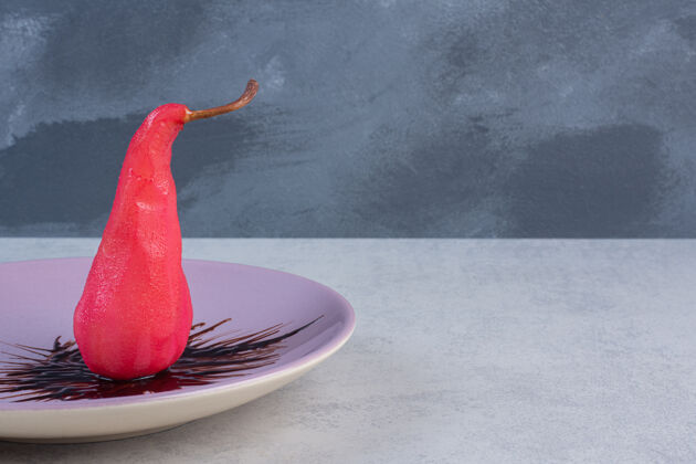 特写新鲜的红梨子和巧克力放在紫罗兰色的盘子里梨生态食物