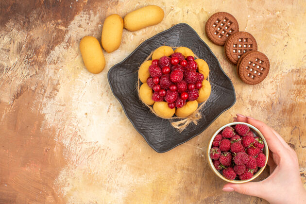饼干新鲜出炉的礼品蛋糕放在棕色盘子上 饼干和水果盘子放在五颜六色的桌子上零食甜点水果