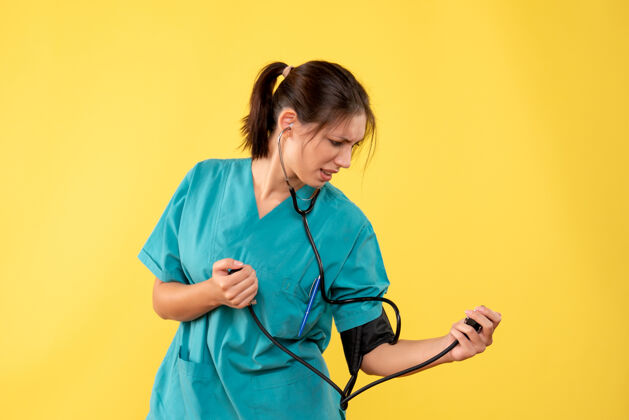 健康前视图穿着医用衬衫的女医生正在检查黄色背景上的压力医疗前面衬衫