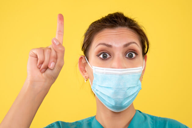 医疗正面近距离观看黄色背景上戴着无菌口罩的女医生面罩护士专业