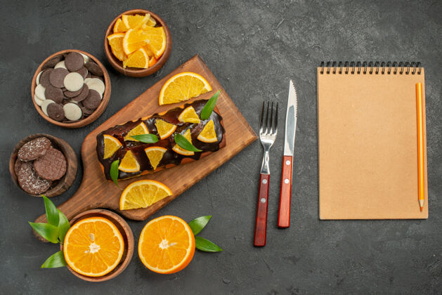 食物在木制砧板上放软蛋糕 用树叶切橘子 饼干和笔记本木头叶子纸