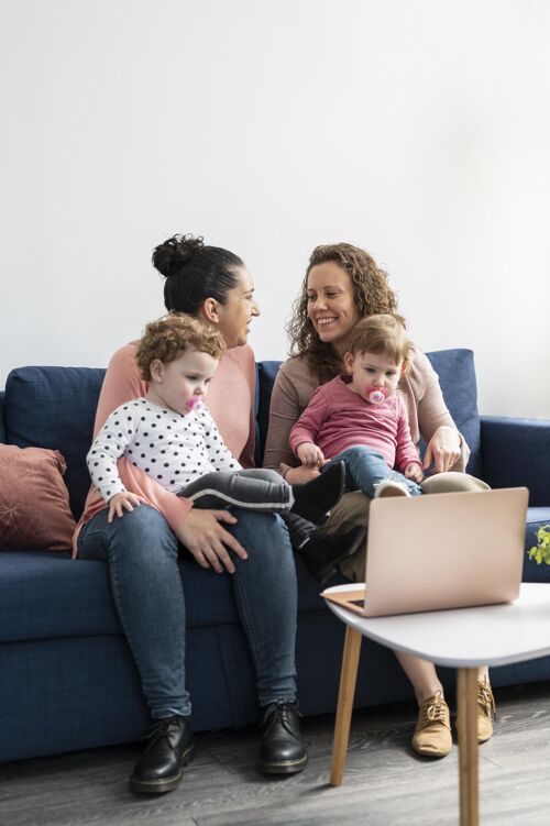 女同性恋夫妇Lgbt妈妈在家 孩子在沙发上妈妈垂直同性恋者