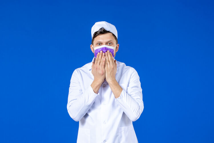 大流行身穿医疗服 戴着紫色面具的男医生在蓝色的脸上亲吻的正面照片药品管道病毒