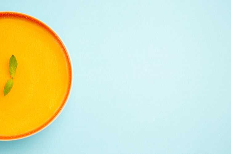 杯子蓝色背景上南瓜汤的顶视图阳光柠檬颜色