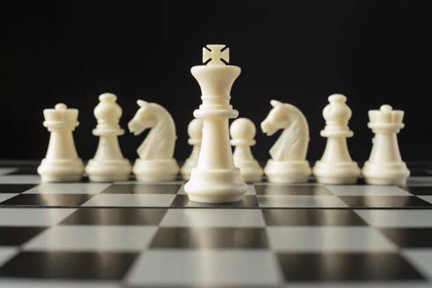 黑棋盘上的白色棋子国王的概念小雕像策略娱乐