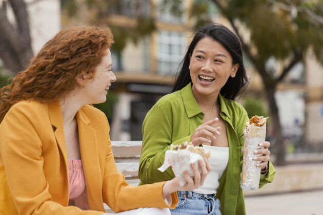 城市快乐的女人一起吃街头美食女性街头食品小吃