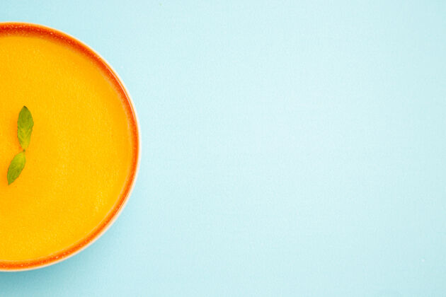 杯子蓝色背景上南瓜汤的顶视图阳光柠檬颜色