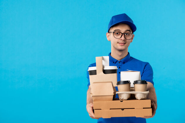 制服男性快递员的正面图 蓝色是咖啡和食品盒笔记本电脑服务快递