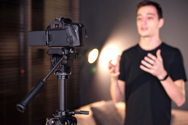 远程男人对着摄像机说话 在虚拟博客里记录自己在家工作年轻的内容创造者视频显示器电脑