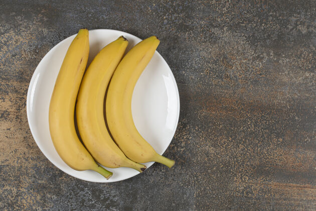 健康白盘子里放三个熟香蕉成熟热带农业
