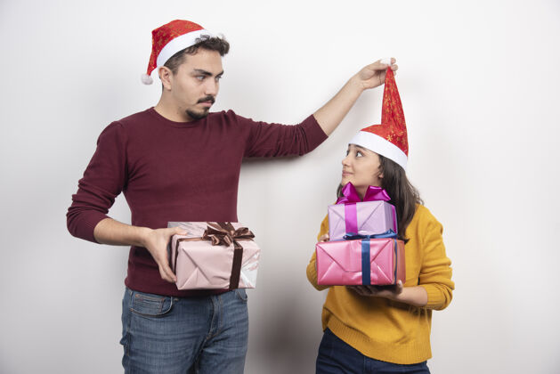 情侣一对年轻漂亮的新人 戴着圣诞帽 手里拿着圣诞礼盒圣诞老人节日礼物