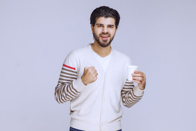 人类一个穿着白衬衫的男人拿着一个咖啡杯享受着它拇指员工照片