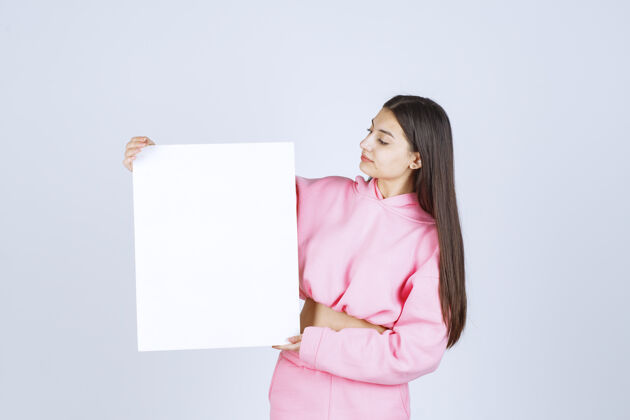 报告穿着粉色睡衣的女孩拿着一个新项目的空白正方形展示板女人年轻人晋升