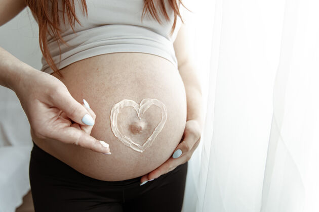出生一位未来母亲怀孕最后几个月的裸体腹部特写镜头 涂上了一层心霜胃腹部期望
