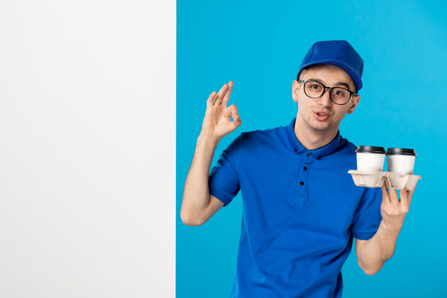 咖啡身穿蓝色制服的男信使的正面图 蓝色上有咖啡工作男信使服务