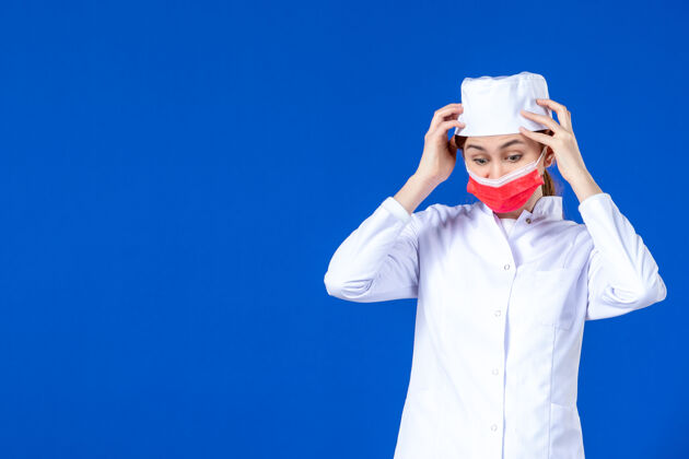 年轻护士身穿医疗服的年轻护士的正视图 蓝色的面具上有红色的面具医院衣服疾病