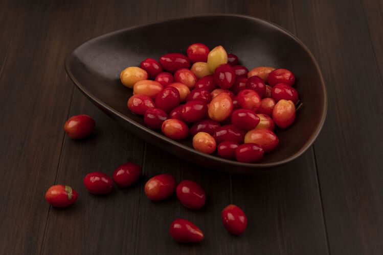 配料木制表面上的棕色碗上的酸的新鲜的山茱萸樱桃的俯视图美味饮食营养