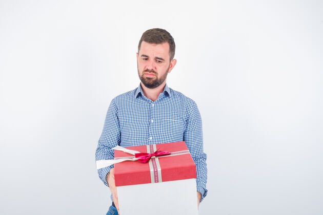 模特年轻的男人拿着礼物盒 看起来很失望 正面看时尚礼物严肃