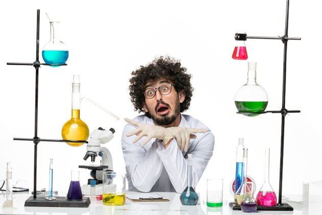 男化学家正面图身着医疗服的男性化学家正坐在桌子前面 浅白的空间里放着溶液化学实验溶液