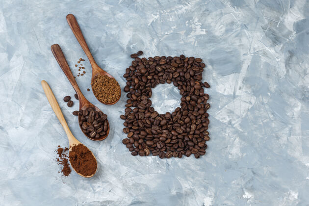 食物一套咖啡豆 速溶咖啡 咖啡粉在木制勺子和咖啡豆在浅蓝色大理石背景特写味道咖啡馆拿铁
