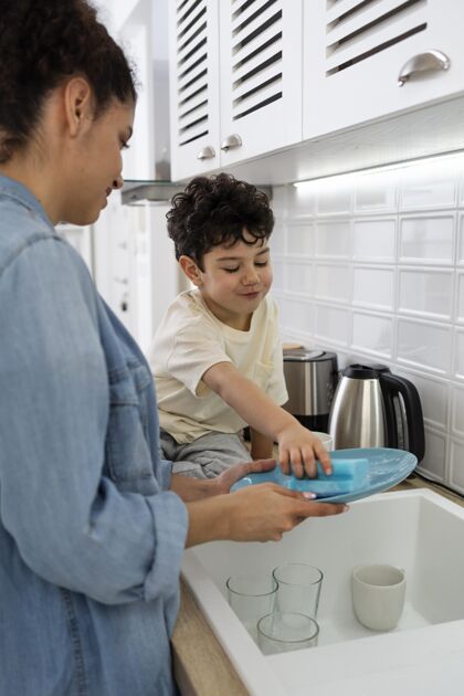 熟悉妈妈和儿子在厨房洗碗幸福的人孩子优质的时间