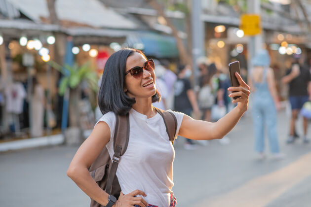 人快乐年轻的亚洲女人用手机旅行 在街上放松旅游肖像旅游