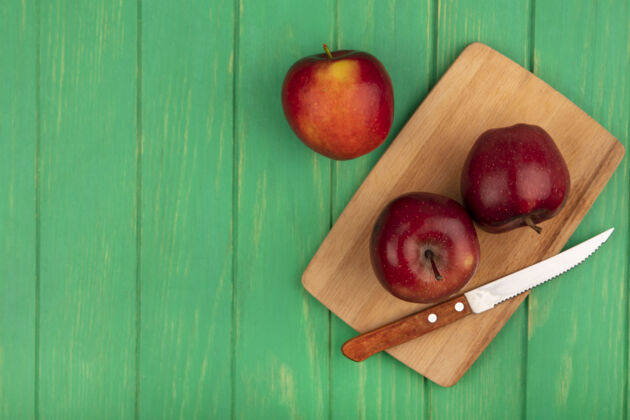 中心顶视图美味的红苹果在一个木制厨房板上与刀子在一个绿色的木制表面与复制空间等级配料食品