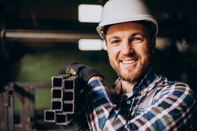 工作场所戴安全帽的工人在工厂里和金属结构一起工作工作员工建筑