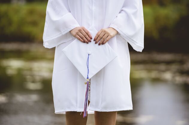 知识一个戴着白色帽子和长袍的女毕业生的低角度特写镜头漂亮学校男性