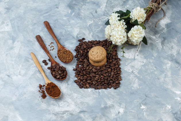 友谊平铺饼干 配咖啡豆 速溶咖啡 咖啡粉 放在木勺子里 浅蓝色大理石背景上的花水平面粉杯子女性
