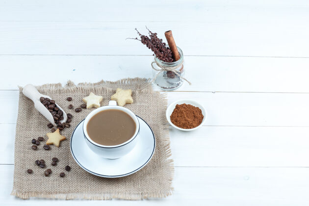 块星星饼干 咖啡豆 一个袋子上的一杯咖啡 一碗速溶咖啡 一罐草药 白色木板背景上的高角度视图艺术食物罐子
