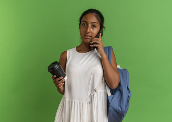 抱着年轻的女学生背着背包拿着一杯咖啡讲电话年轻人背包学生