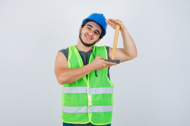好看年轻的建筑工人穿着工作服展示锤子大小 看上去很高兴 正面视图健康英俊成年人