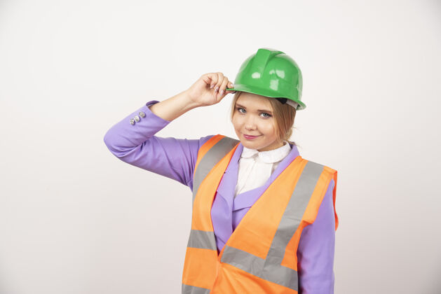年轻人白墙上戴着头盔的年轻女建筑工人人安全帽头盔
