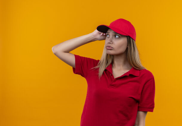 橙色看着一边想着的年轻送货员 穿着红色制服 戴着帽子 手放在头上壁板制服穿