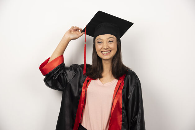 女人应届毕业生穿着礼服在白色背景上摆姿势学术女人帽子