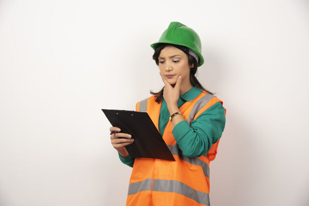 肖像体贴的女工业工程师 穿着制服 白色背景上有剪贴板个人建筑头盔