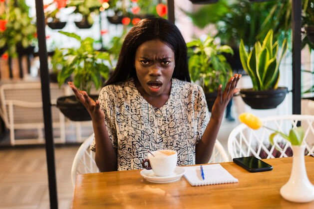 白日梦年轻困惑的非洲女人在咖啡店震惊了咖啡桌子赛车