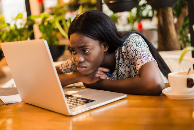 无聊一个疲惫的年轻非洲妇女坐在桌旁的笔记本电脑 而在咖啡馆睡觉的肖像失败人睡眠