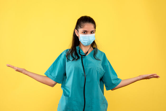 手正面图身着制服的年轻女医生张开双手站在黄色背景上男人护士专业