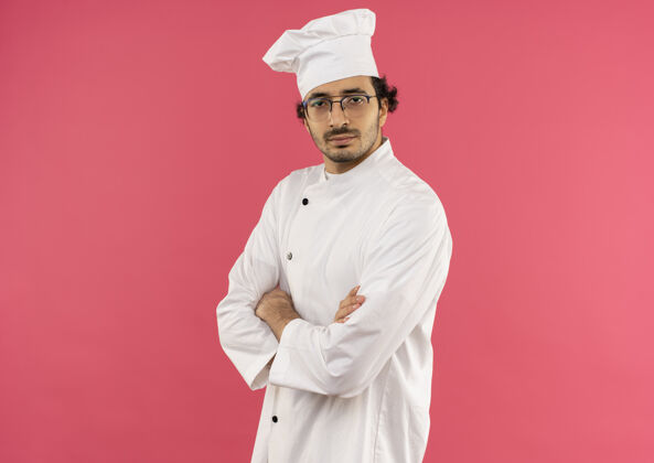 男性自信的年轻男厨师穿着厨师制服和眼镜双手交叉制服厨师年轻
