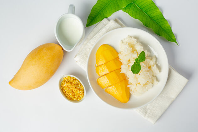 食物新鲜成熟的芒果和糯米与椰子奶在白色的表面美味奶油特写