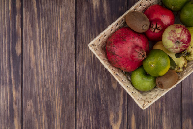 食品顶视图复制空间石榴与橘子苹果梨和猕猴桃在一个篮子在木墙上苹果水果篮子